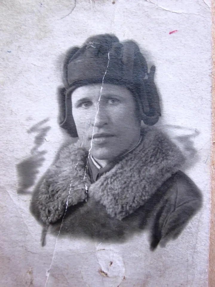 An old damaged photo of a soldier in a tank helmet